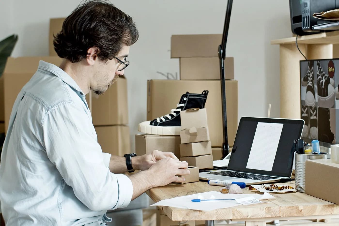 A business owner packing products beside a laptop.